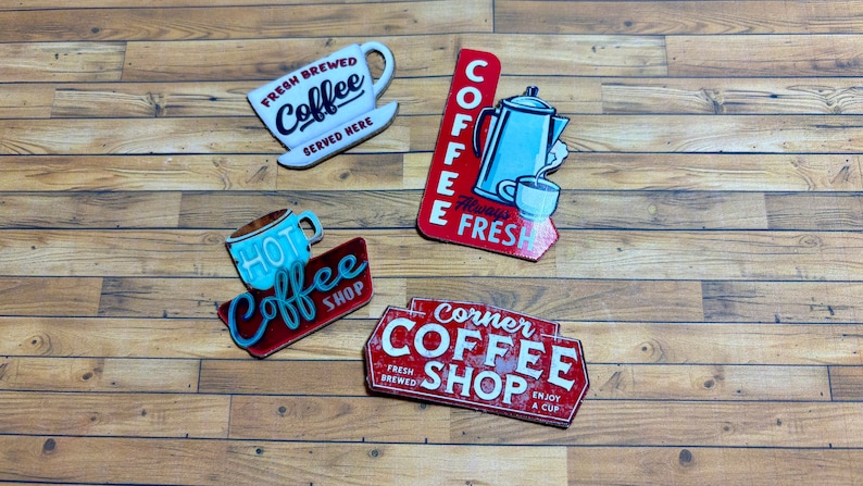 May include: Four vintage-style metal signs with red, white, and blue accents advertising a coffee shop. The signs feature the words "Fresh Brewed Coffee", "Hot Coffee Shop", "Coffee Always Fresh", and "Corner Coffee Shop".