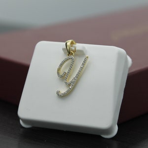May include: A gold pendant in the shape of the letter Y, encrusted with small clear diamonds.