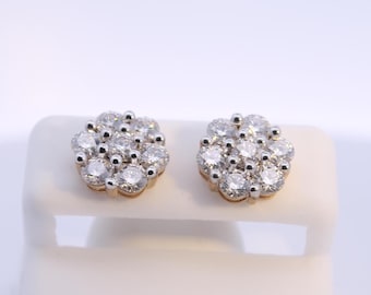 May include: A pair of stud earrings with a cluster of round diamonds. The diamonds are set in a gold-tone metal, forming a floral design. The earrings are presented on a white surface.
