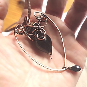 May include: A copper wire heart-shaped pendant with a black glass teardrop charm and a black crystal bead.