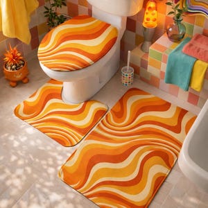 May include: A retro-style bathroom set featuring a toilet seat cover and two matching rugs. The set has a wavy pattern in shades of orange, yellow, and cream. The bathroom also includes a white toilet, a lava lamp, and colorful towels.