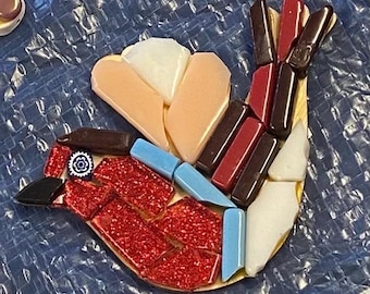 May include: A mosaic bird made of glass tiles in shades of red, white, blue, and brown. The bird has a red body, white wings, and a blue eye.