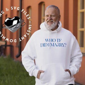 Puede incluir: Una sudadera con capucha blanca con texto azul que dice "WHO TF DID I MARRY?" La persona que lleva la sudadera está de pie frente a un edificio de ladrillo rojo.