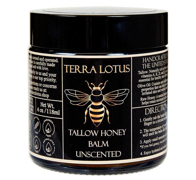 以下が含まれることがあります： 「TERRA LOTUS TALLOW HONEY BALM UNSENTED」と金色で書かれた黒い瓶。ラベルにはミツバチのイラストと、牛脂、オリーブオイル、生蜂蜜などの成分が記載されています。瓶には4オンスまたは118ミリリットルのバームが入っています。