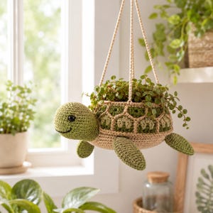 May include: A hanging crochet turtle planter featuring a light green head with black eyes and a shell crafted from alternating shades of green and beige yarn. The turtle is suspended by beige crocheted cords and contains a small green plant.