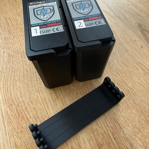 Set of four black PETG-CF battery levers next to two Carplounge smart batteries