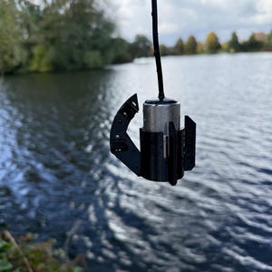 Stainless Carplounge Winchcam camera hanging straight down in the black anti-spinner, lake in the background