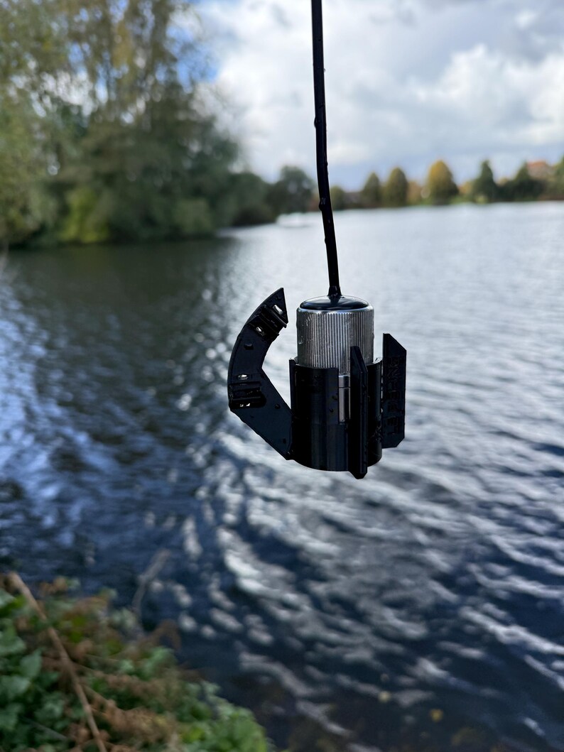 Stainless Carplounge Winchcam camera hanging straight down in the black anti-spinner, lake in the background