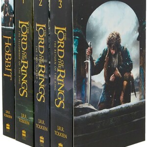 Puede incluir: Un estuche de libros que incluye "El Hobbit" y la trilogía "El Señor de los Anillos". Las lomos de los libros son negros con letras doradas. La ilustración de la caja muestra un personaje sosteniendo una espada en un paisaje nevado. El autor, J.R.R. Tolkien, está impreso.