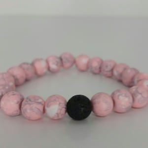 May include: Pink and white marbled bead bracelet with a black lava bead.