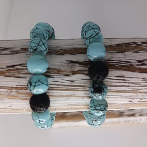 May include: Two bracelets with turquoise blue and black patterned beads and black lava rock beads.
