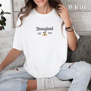 Puede incluir: Camiseta blanca con un gr&aacute;fico negro de Mickey Mouse y el texto "Disneyland EST 1955".