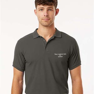 May include: A dark gray polo shirt with short sleeves and a collar. The shirt has a two-button placket and a small white text that says "Your custom text or LOGO" on the chest. The person is wearing a black belt.