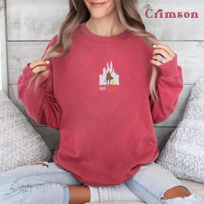 May include: A crimson red sweatshirt with a white silhouette of a castle and a figure holding a lightsaber. The text "Dad I'm Your Yoda" is printed below the image.