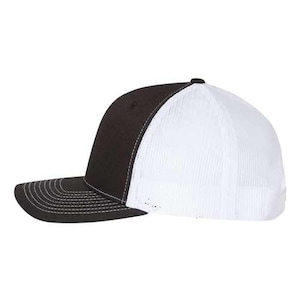 Pu&ograve; includere: Un cappello da camionista nero e bianco con una rete sul retro. La parte anteriore del cappello &egrave; nera e la parte posteriore &egrave; bianca.