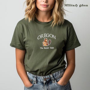 以下が含まれることがあります： ビーバーの白いグラフィックと「OREGON The Beaver State」のテキストが書かれた緑色のTシャツです。