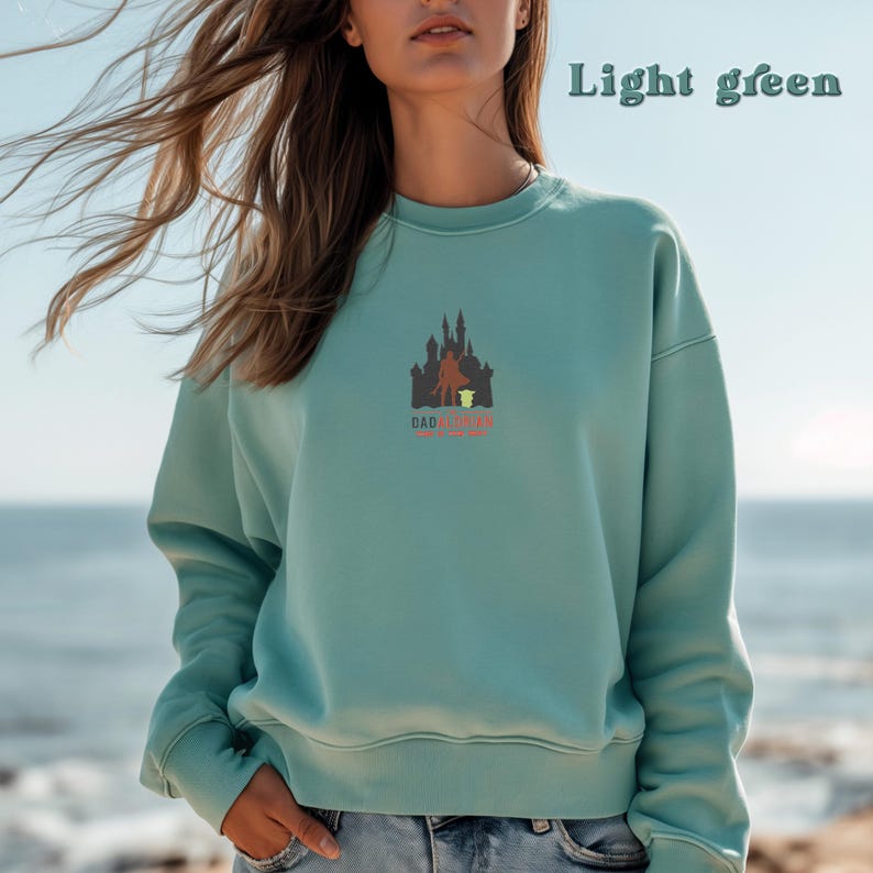 May include: A light green sweatshirt with a graphic of a castle and the text "Dadalorian" printed on the front.