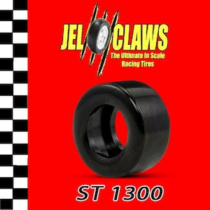 May include: A black rubber tire with the text "ST 1300" printed on the bottom. The tire is for a model car and has a smooth surface. The tire is a part of a set of racing tires called "JeloClaws: The Ultimate In Scale Racing Tires".