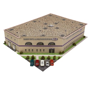 Puede incluir: Maqueta de un edificio comercial con exterior beige, techo texturizado y franja morada. El edificio tiene el texto "RUBBER PARTS and WEATHERSTRIPPING SUPERIOR" y un logotipo. Hay coches en miniatura aparcados delante.