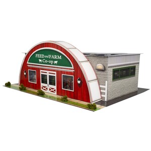 Puede incluir: Una maqueta en miniatura de un edificio Feed and Farm Co-op con una fachada arqueada roja, puertas dobles blancas, un letrero verde con texto blanco y una sección lateral de ladrillo gris con ventanas. Arbustos verdes decoran la base frontal.