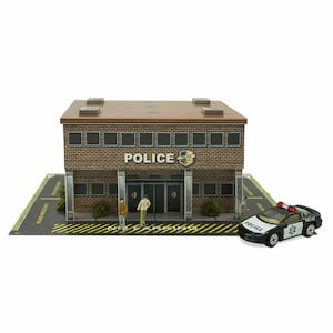 以下が含まれることがあります： レンガ造りの警察署のミニチュアモデルで、白黒の警察車両が前に駐車されています。警察署には「POLICE」と書かれた看板と、看板の上に小さな警察のバッジがあります。警察署の前には、ミニチュアの人形が3体立っています。
