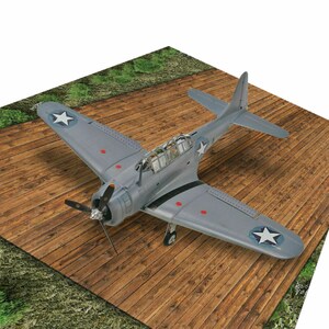 May include: A gray and white model airplane with red markings on a wooden surface. The airplane has a star on the wing and a propeller on the front.