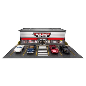 May include: A miniature model of a Race Track Express store building with a grey facade, red awnings, and glass windows. Four toy cars in white, blue, red, and black are parked in the front lot, which features yellow parking lines and a crosswalk.