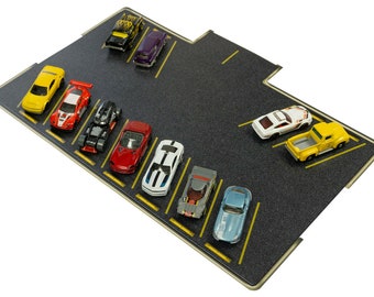 May include: A black asphalt parking lot with yellow lines and ten toy cars parked in the spaces. The cars are a mix of red, white, yellow, and blue.