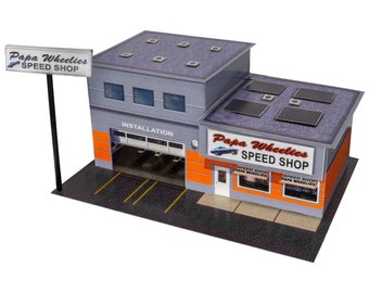 May include: A model of a Papa Wheelies Speed Shop building with a gray roof, orange and white walls, and a sign that says "Papa Wheelies Speed Shop".