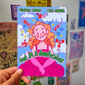 Puede incluir: Una colorida impresión artística con una ilustración de dibujos animados de una persona con un vestido rosa y cabello naranja, rodeada de figuras de animadoras. El texto dice "Natasha Lyonne Clea Duvall" y "but I'm a cheerleader" sobre un fondo azul.