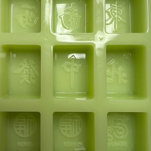 May include: A green silicone mold with nine individual squares, each containing a raised Chinese character. The characters are:  '風', '發', '中', '發', '白', '中', '發', '發', '白'.