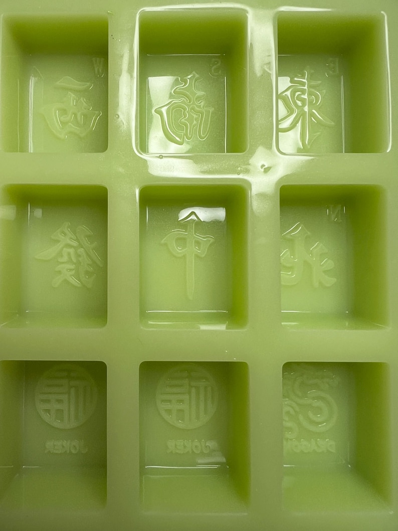 May include: A green silicone mold with nine individual squares, each containing a raised Chinese character. The characters are:  '風', '發', '中', '發', '白', '中', '發', '發', '白'.