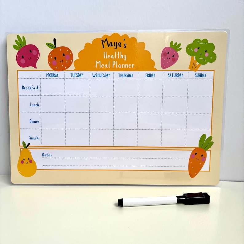 Puede incluir: Un planificador de comidas semanal beige con el texto "Maya's Healthy Meal Planner". Presenta una cuadr&iacute;cula para las comidas diarias, decorada con frutas y verduras de dibujos animados. Se incluye un marcador en blanco y negro.