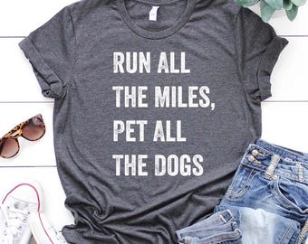 May include: Gray t-shirt with the text "Run all the miles, pet all the dogs" printed in white.
