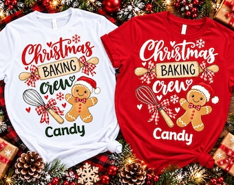 May include: A white t-shirt and a red t-shirt, each featuring a graphic of a rolling pin, a whisk, and a gingerbread person wearing a Santa hat. The text reads Christmas BAKING crew Candy, accented with red and white plaid bows and small hearts.