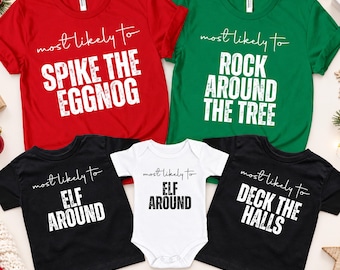 May include: A collection of five shirts and a baby bodysuit featuring holiday-themed text. The red shirt reads 'most likely to SPIKE THE EGGNOG', the green shirt 'most likely to ROCK AROUND THE TREE', two black shirts 'most likely to ELF AROUND' and 'DECK THE HALLS', and the white bodysuit 'most likely to ELF AROUND'.