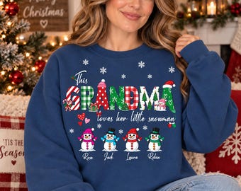 May include: A navy blue long-sleeve sweatshirt featuring the text This GRANDMA loves her little snowman in colorful patterns. Below the text are four illustrated snowmen with the names Rose, Jack, Laura, and Robin printed underneath them.