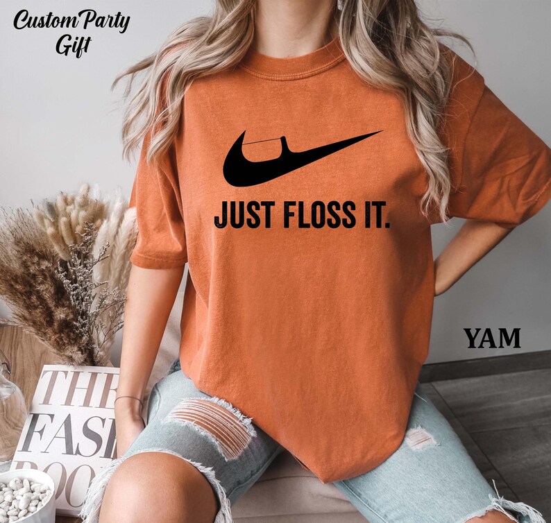 a woman wearing an orange shirt that says just floss it