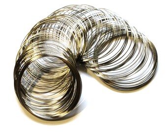 May include: A collection of silver-colored metal rings, tightly coiled together, arranged in a curved shape against a white background. The rings appear to be made of thin wire, reflecting light and creating a shiny appearance. The overall effect is of a decorative or craft element.