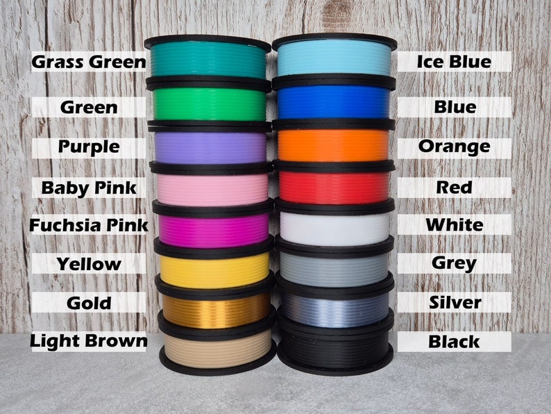 May include: A collection of 16 spools of filament for 3D printing, arranged in two rows of eight. The spools are labeled with their colors, including grass green, green, purple, baby pink, fuchsia pink, yellow, gold, light brown, ice blue, blue, orange, red, white, grey, silver, and black.