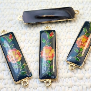 May include: Rectangular dark blue enamel pendants with gold-colored edges and loops. Each pendant features a floral design with a yellow and red rose, green leaves, and a gold stem. The pendants are suitable for jewelry making.