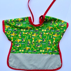 May include: A green and yellow construction vehicle print baby bib with a red trim and a white and gray striped pocket.
