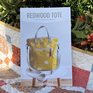 May include: A sewing pattern for a yellow and white polka dot tote bag with a zipper top. The pattern is called "Redwood Tote" and is by Noodlehead.