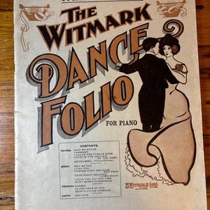 Puede incluir: Una portada de partitura vintage para una pieza de piano titulada "The Witmark Dance Folio" con una pareja bailando en el frente. La portada es beige con texto e ilustraciones en marrón y negro. La partitura es la número cuatro de la serie.