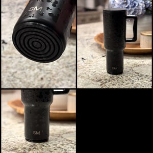 K&ouml;nnte beinhalten: Schwarzer isolierter Becher mit Griff und Strohhalm. Der Becher hat eine strukturierte Oberfl&auml;che und weist ein Muster aus Mickey Mouse-Silhouetten auf. Die Initialen "SM" sind auf dem Becher zu sehen.