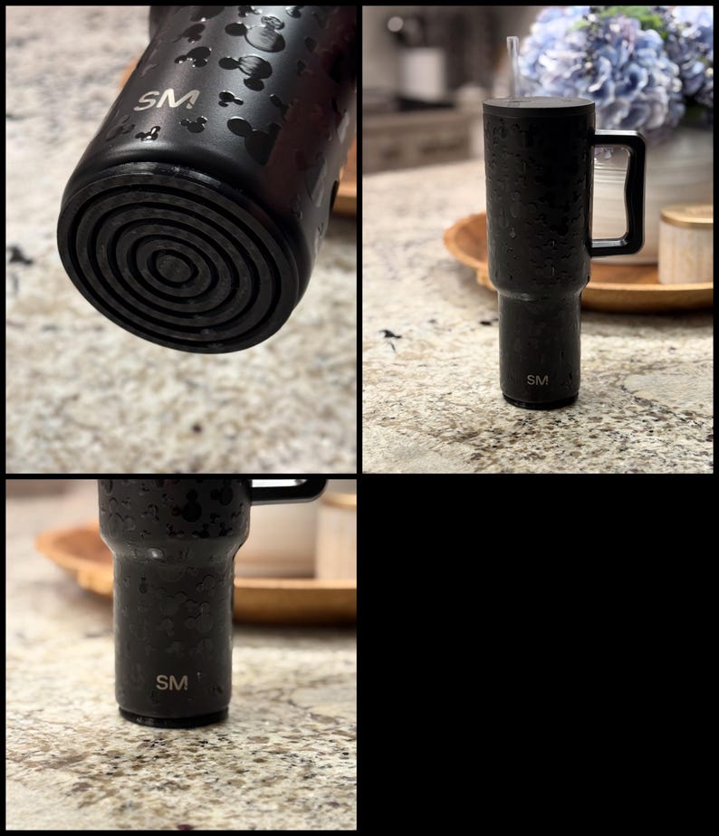 K&ouml;nnte beinhalten: Schwarzer isolierter Becher mit Griff und Strohhalm. Der Becher hat eine strukturierte Oberfl&auml;che und weist ein Muster aus Mickey Mouse-Silhouetten auf. Die Initialen "SM" sind auf dem Becher zu sehen.