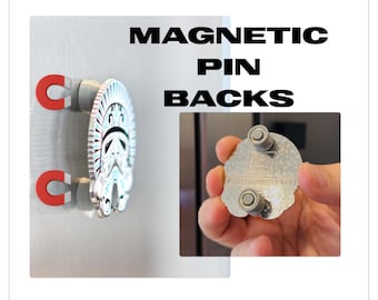 May include: Magnetic pin backs with a silver Stormtrooper design. The text "MAGNETIC PIN BACKS" is displayed in black block letters. The pin is attached to a silver surface with red and silver magnets.