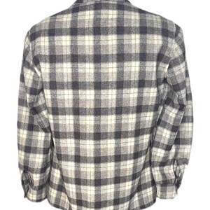 Puede incluir: Camisa de manga larga con botones y un dise&ntilde;o de cuadros cl&aacute;sico en tonos grises, negros y blanco roto. La camisa se muestra en un maniqu&iacute;, mostrando la vista trasera. La tela parece ser de peso medio.