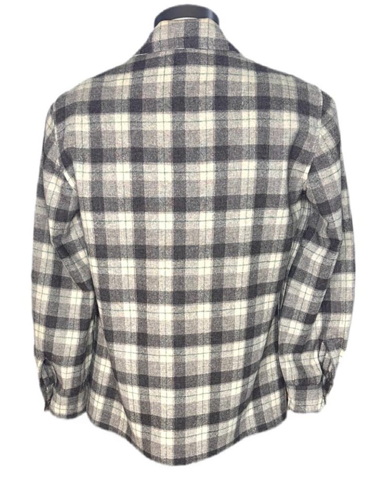 Puede incluir: Camisa de manga larga con botones y un dise&ntilde;o de cuadros cl&aacute;sico en tonos grises, negros y blanco roto. La camisa se muestra en un maniqu&iacute;, mostrando la vista trasera. La tela parece ser de peso medio.