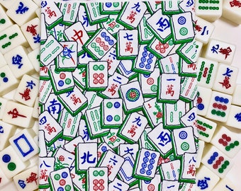 May include: A white fabric bandana with a repeating pattern of green and blue mahjong tiles. The tiles have various Chinese characters and symbols on them.